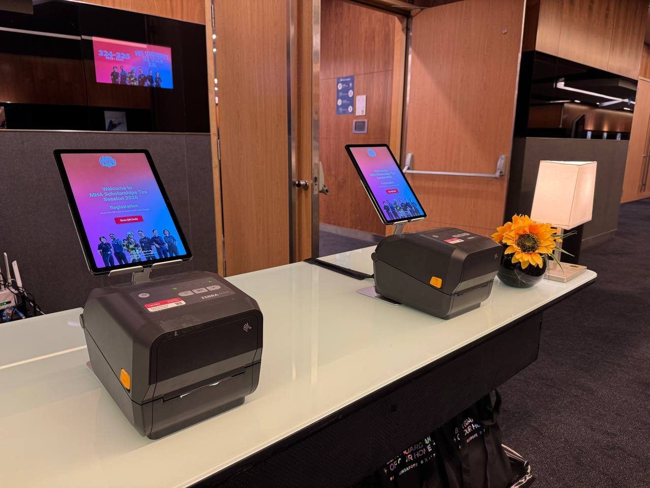 A close-up of two tablet check-in stations and Zebra badge printers at the MHA Scholarships Tea Session